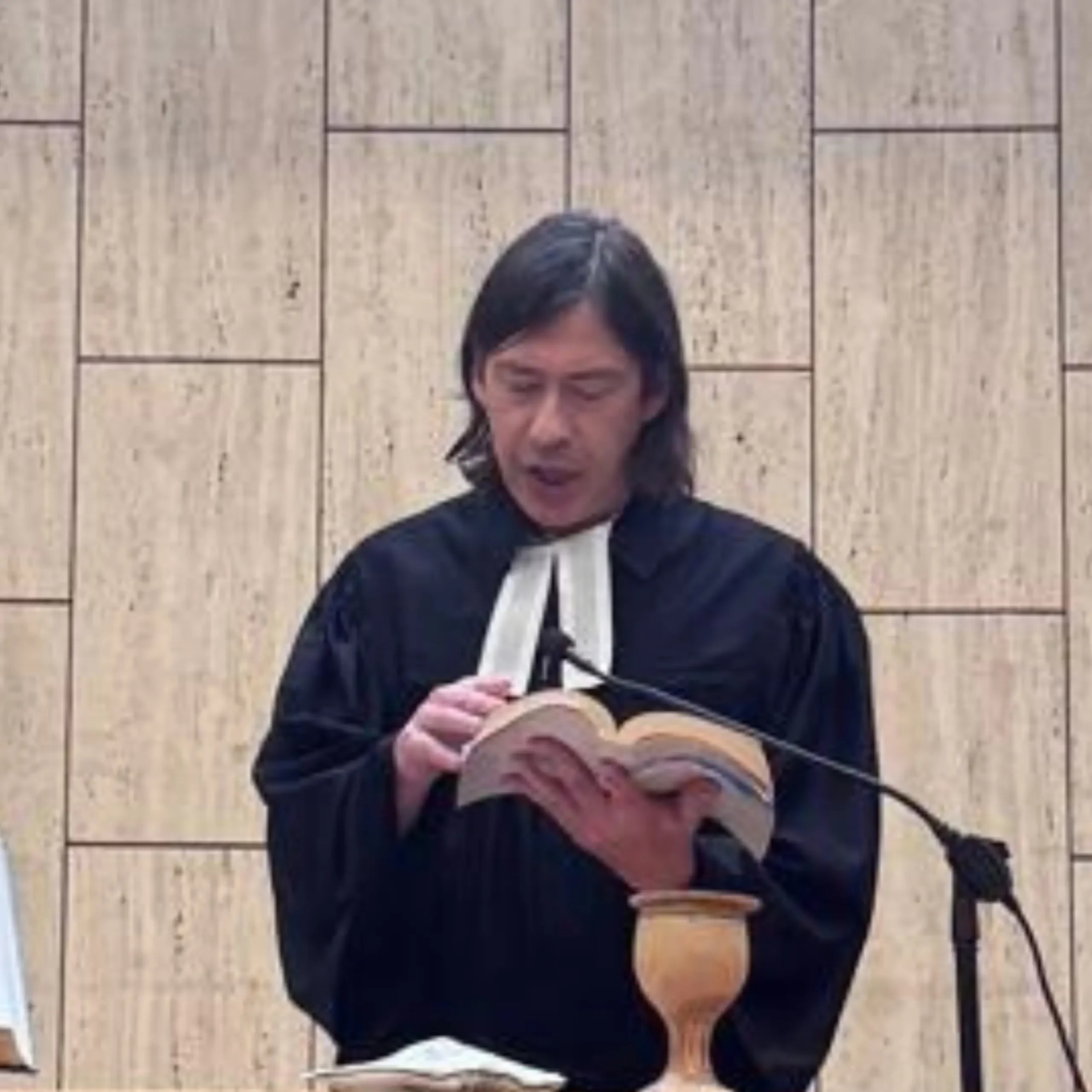 Pastor con toga protestante leyendo la Biblia durante el culto.