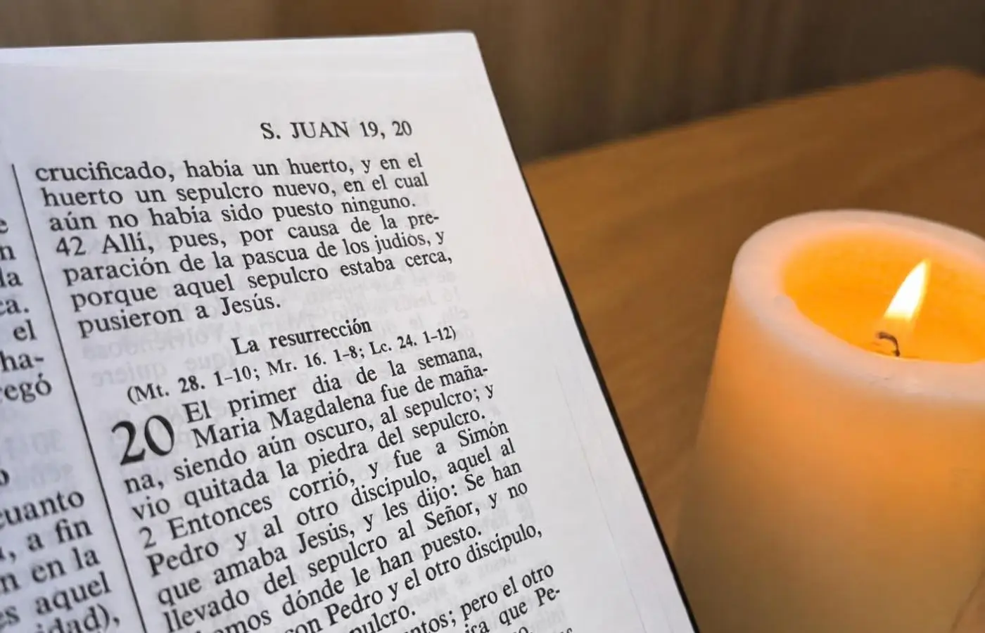 Bíblia oberta al capítol 20 de l'Evangeli de Joan, sobre la resurrecció de Jesús, al costat d'una espelma encesa.