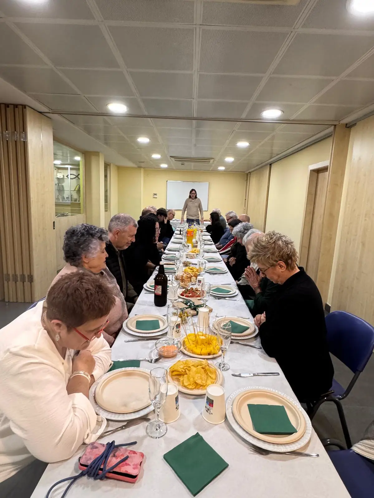 Persones de la comunitat reunides al voltant d’una taula compartint un àpat.